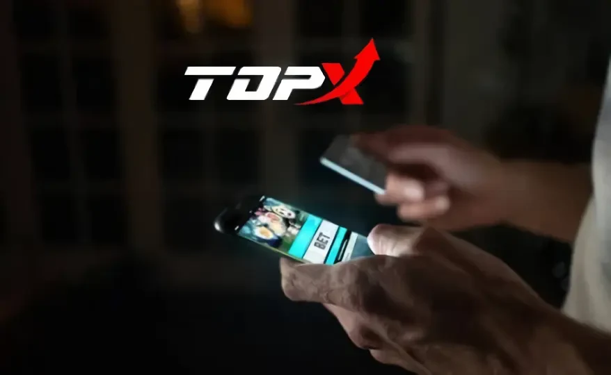 Imagem de marca da TopX: mãos segurando um celular com jogo de cassino na tela